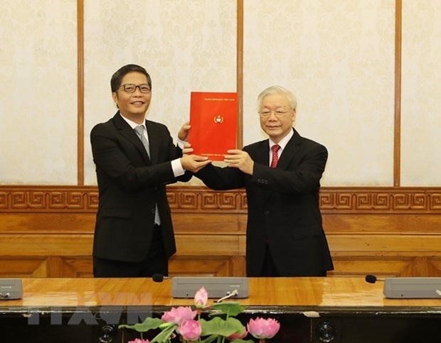 Le secrétaire général du Parti et président Nguyen Phu Trong remet la décision à Tran Tuan Anh. Photo : VNA