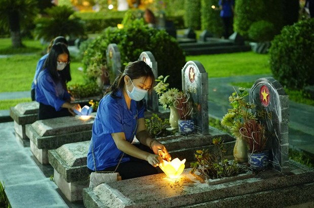 Des jeunes offrent des bâtonnets d'encens aux tombes des Héros morts pour la Patrie. Photo: VNA